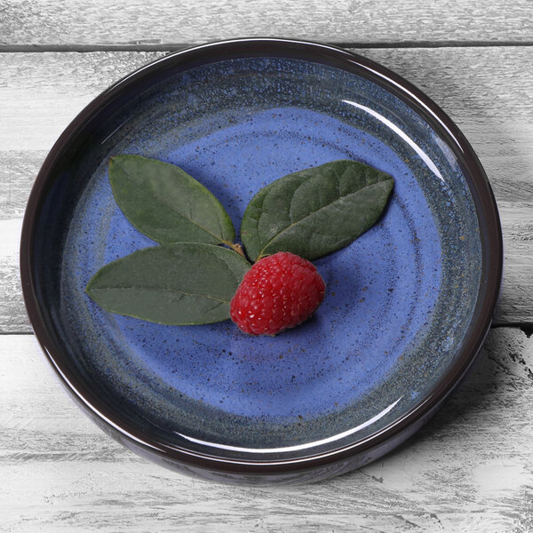 An Elite Global Solutions cobalt blue melamine plate with a raspberry and leaves on it.
