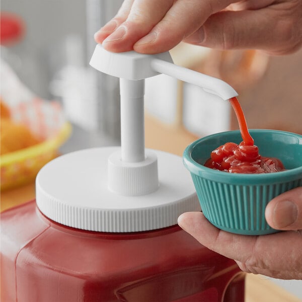 A hand using a Choice condiment pump to pour ketchup into a bowl.