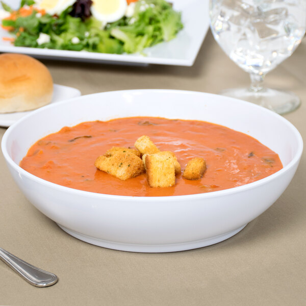A white Siciliano bowl filled with soup with bread on a table.