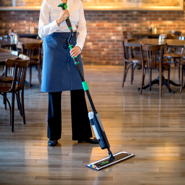 A woman using an Unger Excella floor cleaning kit in a restaurant.