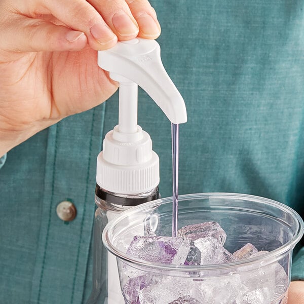 A person using a white Choice flavoring syrup pump to pour purple liquid into a cup of ice.