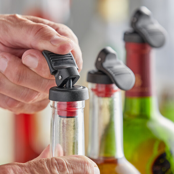 A person using an American Metalcraft bottle stopper to close a bottle of liquid.