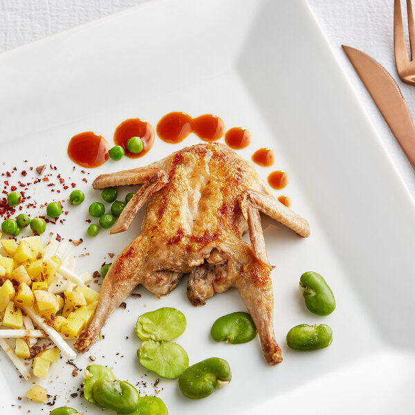 A plate of food with a piece of cooked Manchester Farms quail and vegetables.
