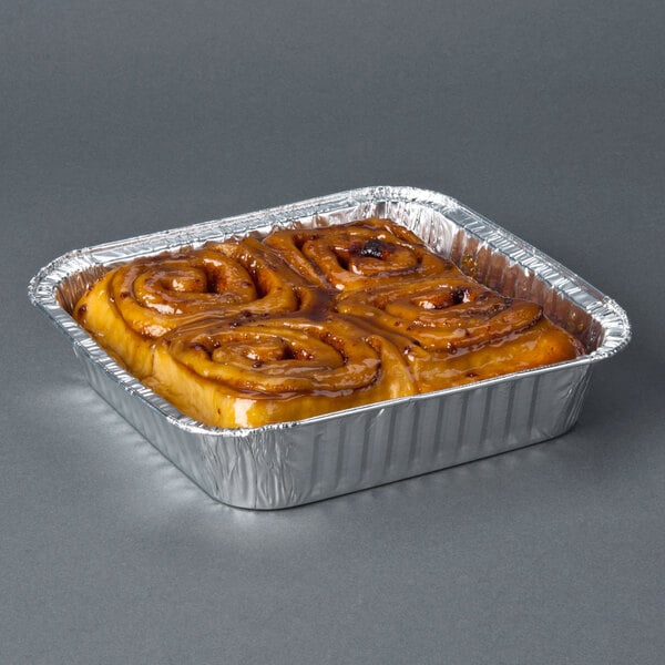 An 8" square foil cake pan with cinnamon rolls in it.