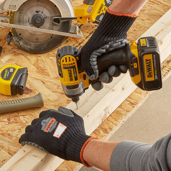 A person wearing Ergodyne ProFlex anti-vibration gloves using a cordless drill to cut wood.