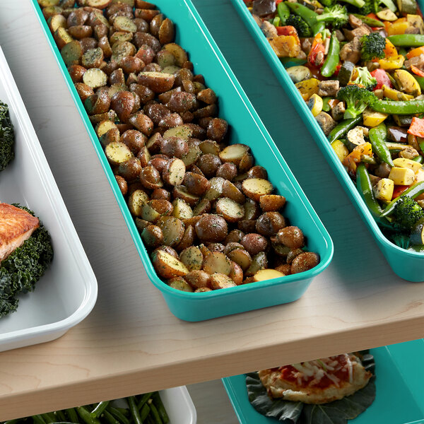A green Cambro tray filled with food on a counter.
