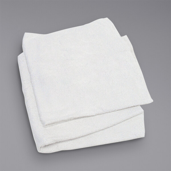 A stack of folded white Hospeco terry cloth towels on a gray surface.