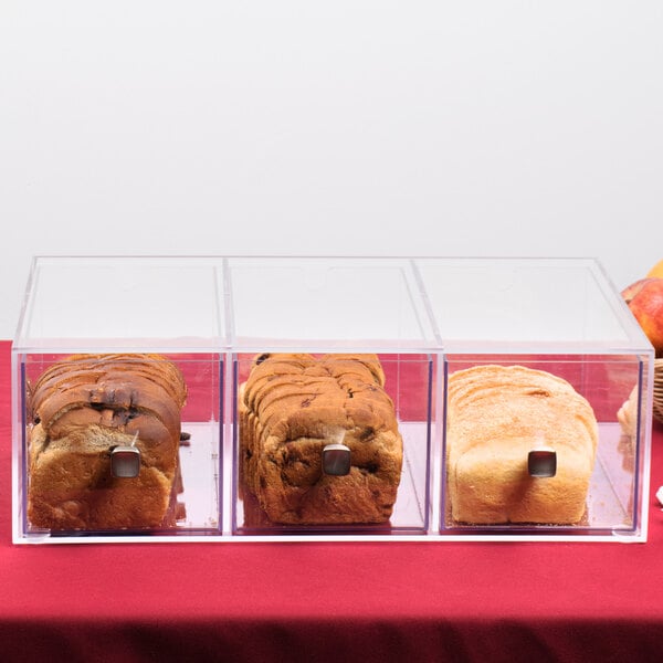 A row of bread loaves in clear plastic containers in a bakery display case.
