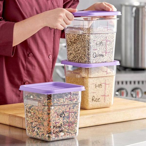 A woman holding a Vigor clear purple-lidded food storage container filled with oats.