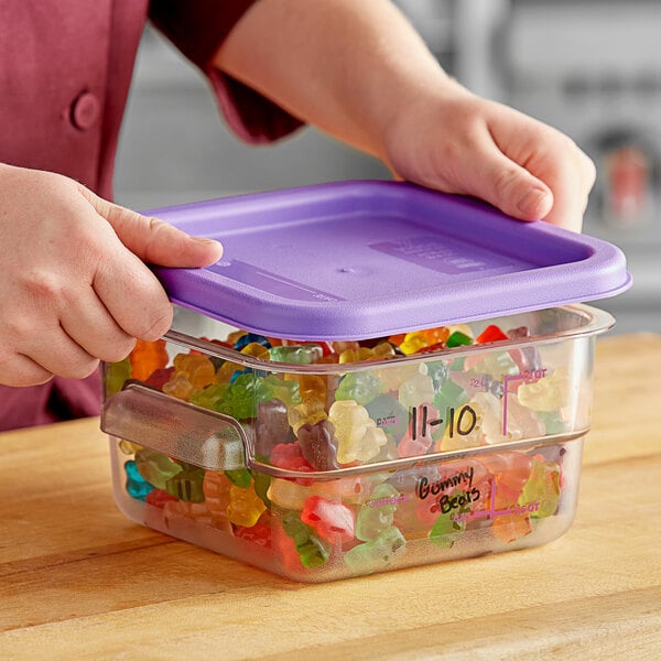 A woman holding a purple Vigor food storage container with gummy bears inside and a purple lid.