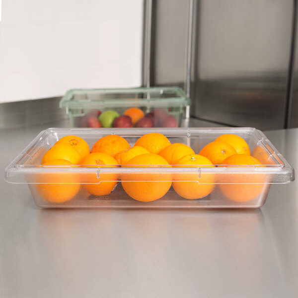 A Carlisle clear plastic food storage container with oranges in it.