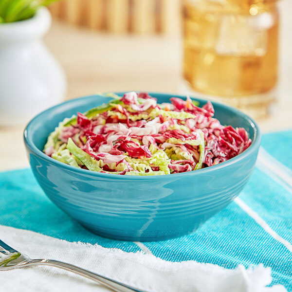 A close-up of a bowl of coleslaw with shredded cabbage in a Caribbean turquoise stoneware bowl.