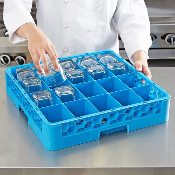 A woman in a white chef's uniform uses a blue Carlisle tilted cup rack to hold clear glasses.