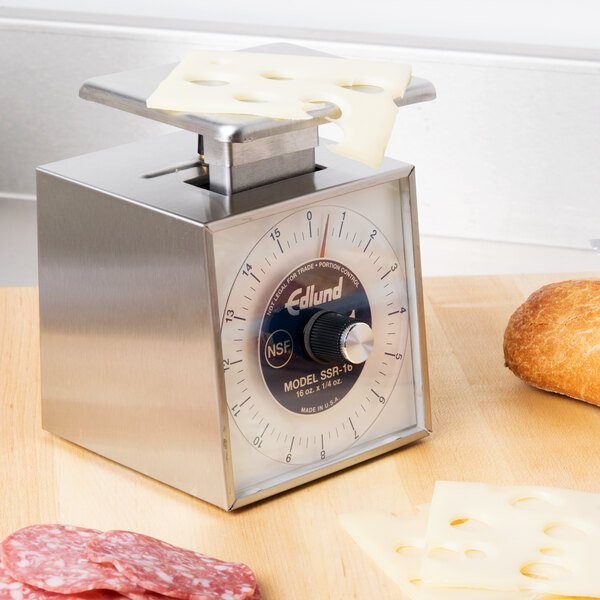 An Edlund mechanical portion scale with a cheese and a piece of bread on it.