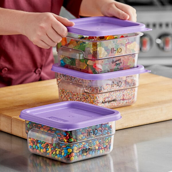 A woman holding a Vigor clear plastic container with a purple lid filled with colorful candies.