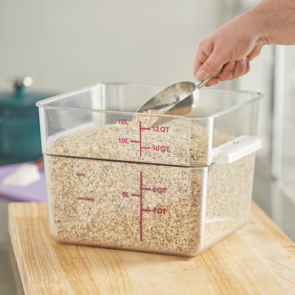 A person pouring oats from a Vigor food storage container into a measuring cup.