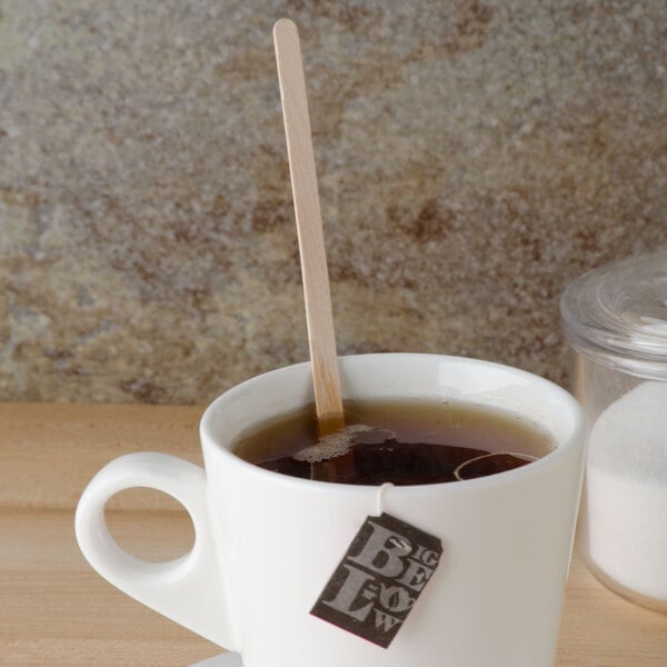 A cup of tea with a Royal Paper wooden coffee stirrer in it.