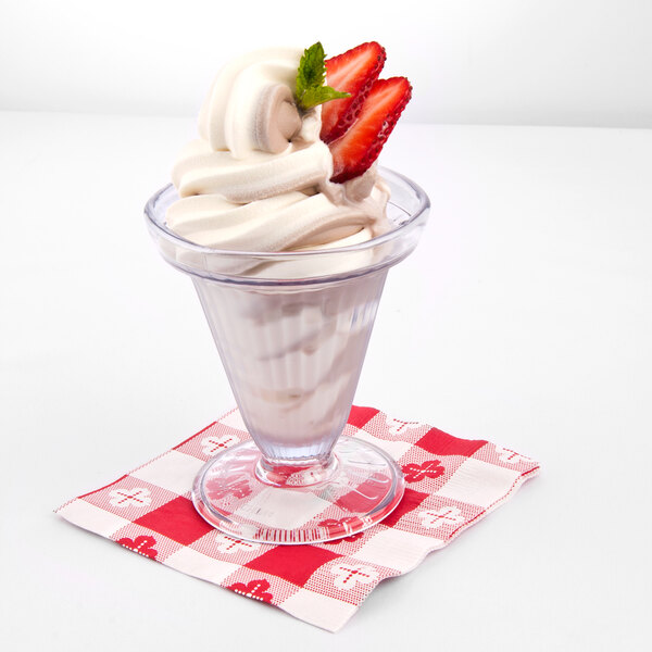 A clear plastic cup of ice cream with strawberries on top.
