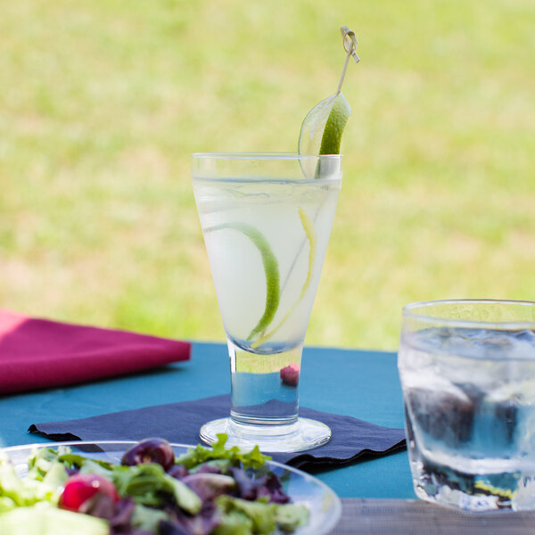 A Libbey Catalina wine goblet filled with water on a table with a plate of salad.