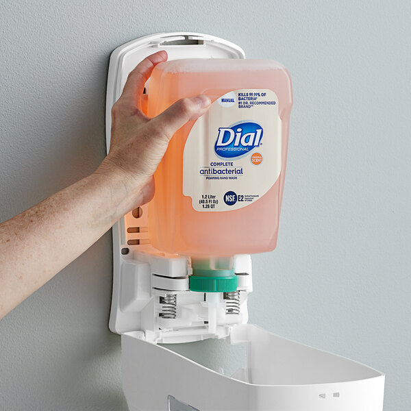 A hand holding a Dial Complete Original foaming hand wash refill bottle.