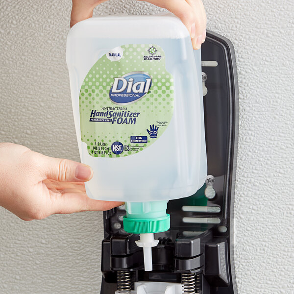 A hand holding a Dial FIT Universal Manual Antibacterial Foam Hand Sanitizer refill container.
