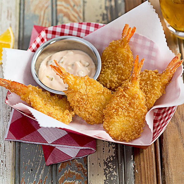A bowl of fried Mrs. Friday's U/10 Size breaded fantail shrimp with sauce.