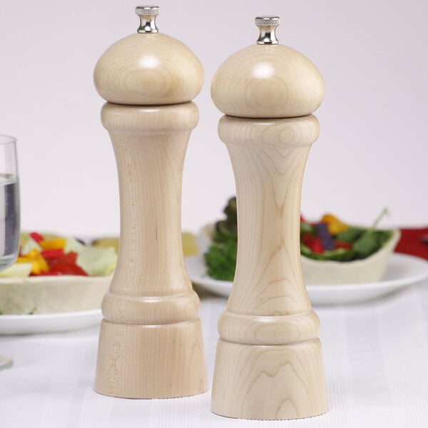 A close-up of a wooden Chef Specialties pepper mill and salt mill on a table.