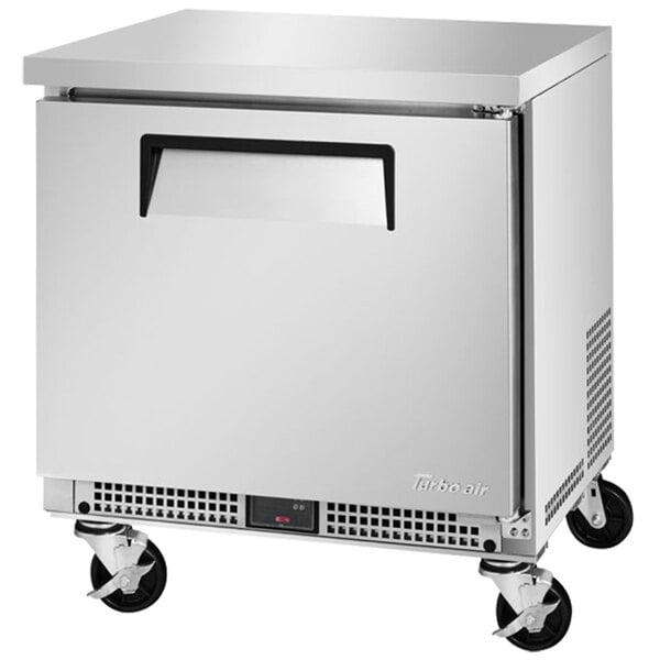 A silver Turbo Air undercounter refrigerator with a solid door and wheels.