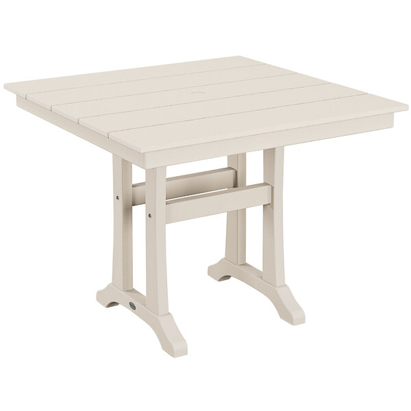 A white POLYWOOD table with wooden legs and a wooden top on an outdoor patio.