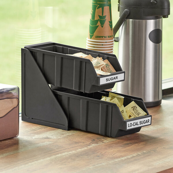 A Choice black 2-tier self-serve organizer with 2 black bins holding sugar packets.