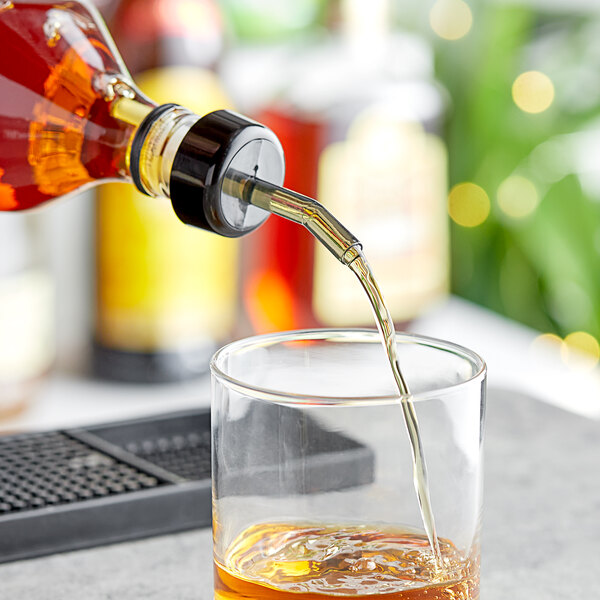 A person using a Choice Smoke Free Flow Whiskey Pourer to pour whiskey into a glass.