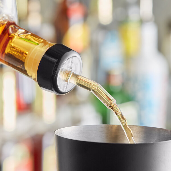 A bartender using a Choice whiskey pourer to pour a drink into a cup.