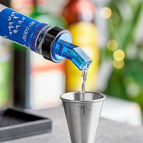 A Choice blue liquor pourer pouring blue liquid into a metal cup.
