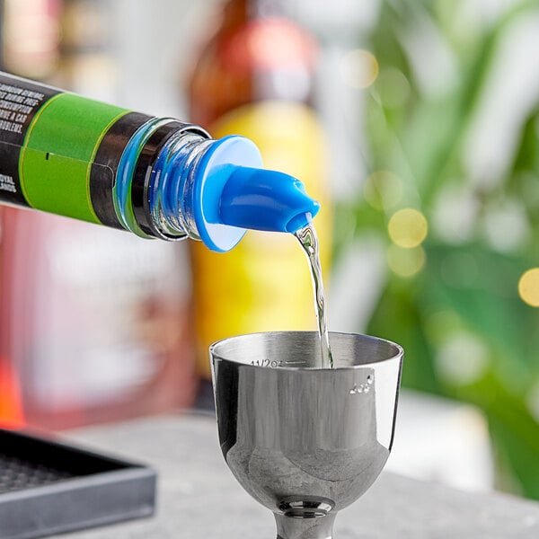 A person using a blue Choice Free Flow Liquor Pourer to pour liquid into a silver cup.