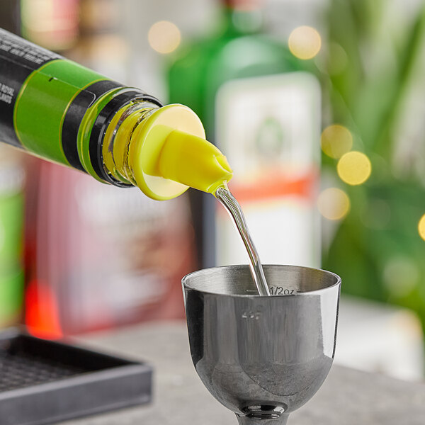 A person using a yellow Choice free flow liquor pourer to pour a drink into a cup.