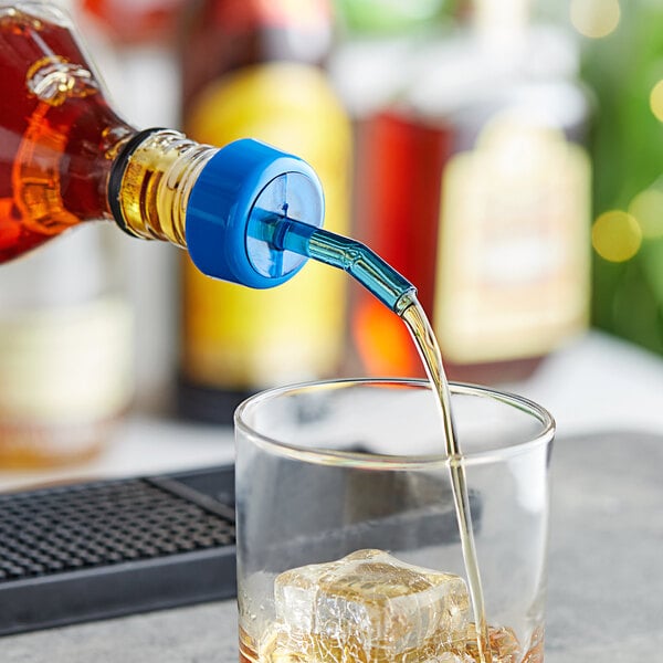 A person using a Choice Blue Free Flow Whiskey Pourer to pour a drink into a glass.