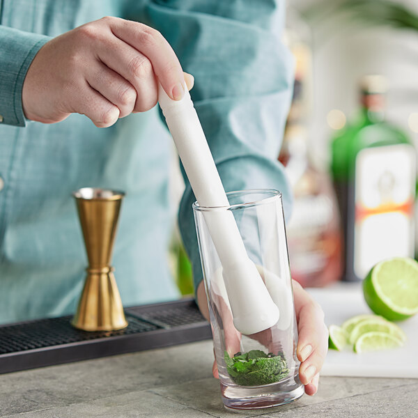 A person using a white Choice muddler in a glass to make a drink.