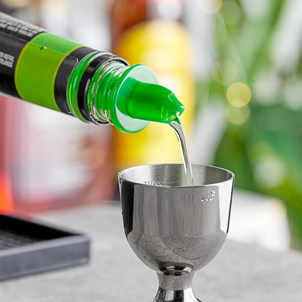 A green liquid being poured into a cup using a green free flow liquor pourer.