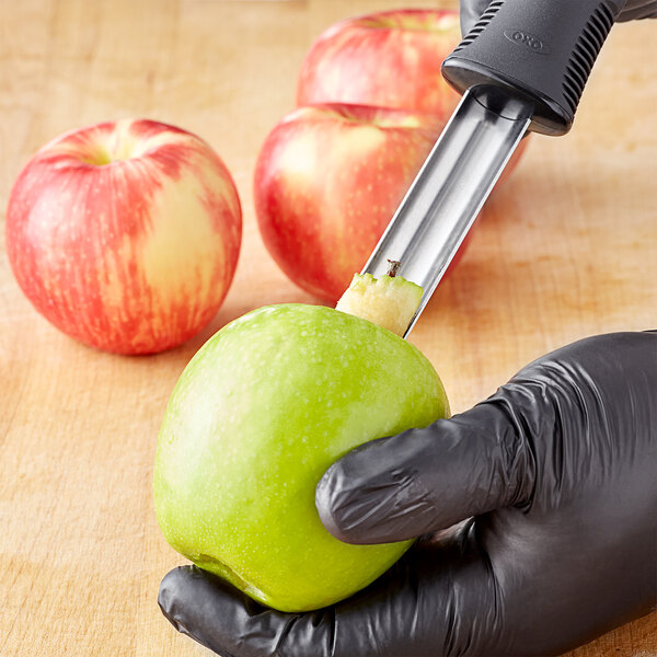 A person using an OXO apple corer to remove the core from an apple.