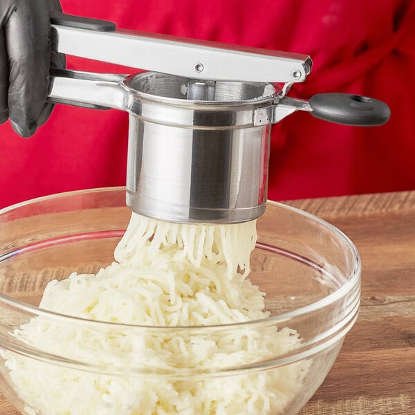 A person using an OXO Good Grips potato ricer to rice potatoes.