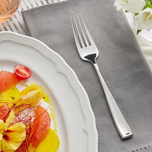 A plate of fruit and vegetables on a table with an Acopa Monte Bianco stainless steel salad fork.