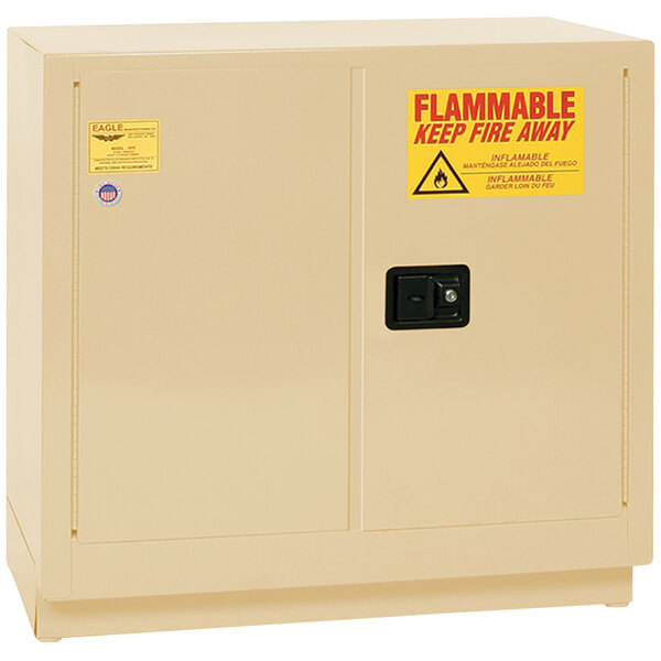 A tan metal Eagle safety cabinet with a yellow and red flammable liquid sign.