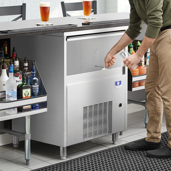 A Manitowoc undercounter ice machine on a counter in a bar.