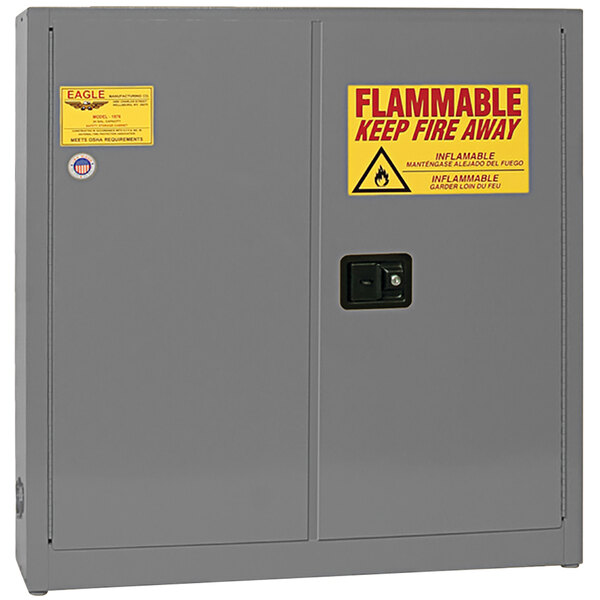 A gray Eagle Manufacturing flammable liquid safety cabinet with yellow and red flammable warning sign.
