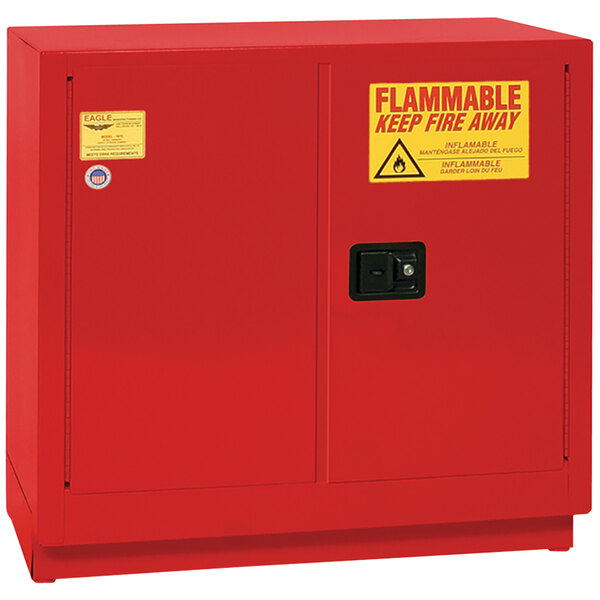A red metal Eagle Manufacturing safety cabinet for flammable liquids with a yellow and red sign.
