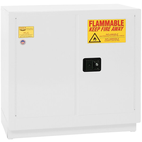 A white metal Eagle Manufacturing safety cabinet with a yellow "flammable" sign and self-closing door.