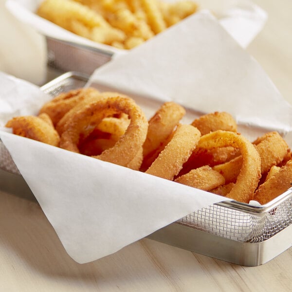 A group of fried onion rings and fries in a white basket lined with a customizable white liner.