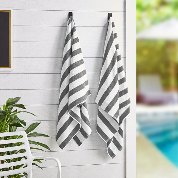 Two Monarch Brands gray striped pool towels hanging on a wall.