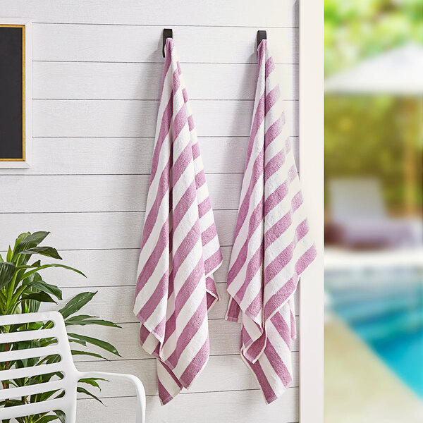 Two Monarch Brands lavender striped pool towels hanging on a wall.