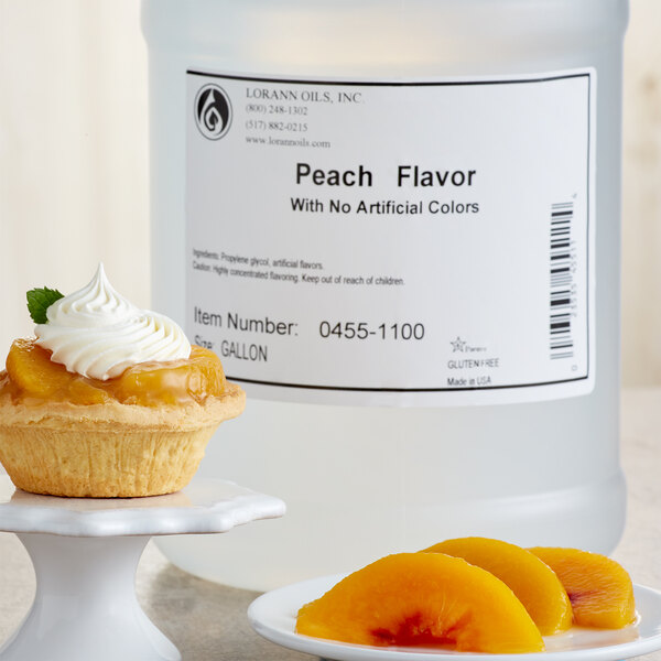 A bottle of LorAnn Oils Peach Super Strength Flavor on a white plate with a pastry and whipped cream.
